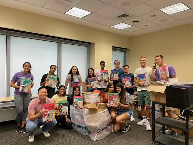 Volunteers holding completed school supply kits in a classroom.