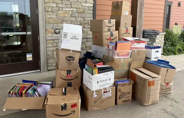 A collection of supply donation boxes stacked beside a building entrance.