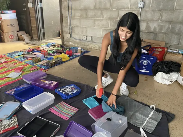 A volunteer sorting school supplies into bags and storage bins.