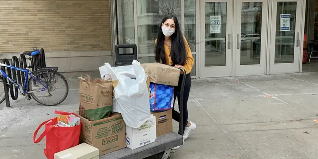 Volunteer standing beside boxes and bags of donated supplies.