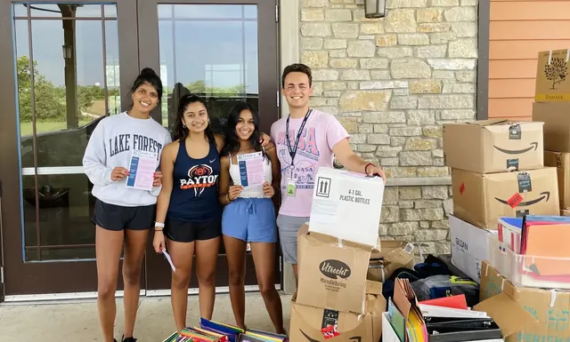 Four volunteers standing beside stacked boxes of collected donations.